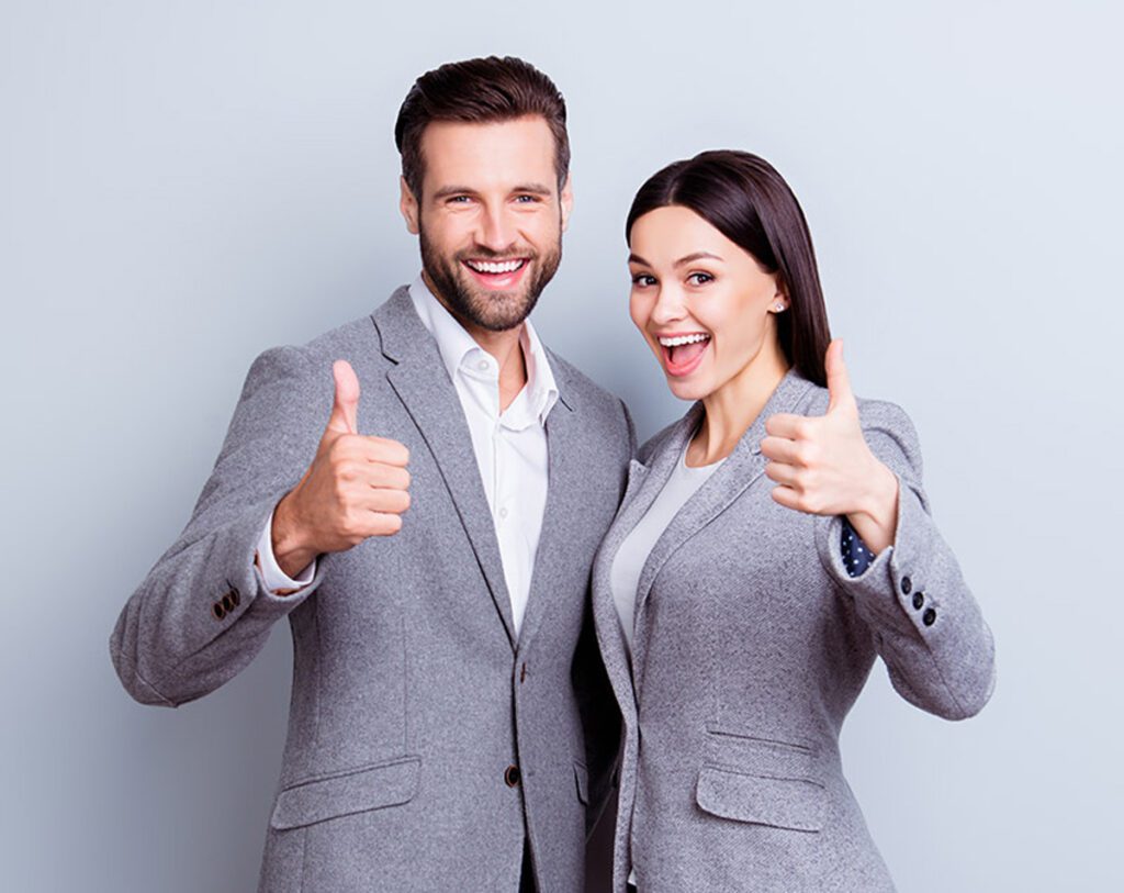 Fröhliches junges Paar vor einer grauen Wand in Business Kleidung bei einem Business Selfie Shooting