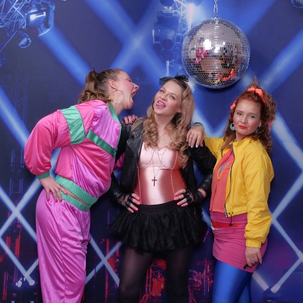 Drei junge Frauen im Selfie Studio in poppigen Kleidern und Discokugeln