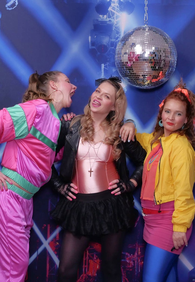 Drei junge Frauen im Selfie Studio in poppigen Kleidern und Discokugeln