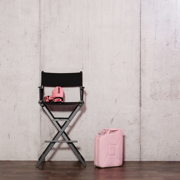 Regiestuhl vor Betonwand mit rosa Boxhandschuhen und Kanister im Selfie Fotostudio